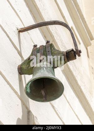An antique old metal vintage bell mounted on the wall. Stock Photo