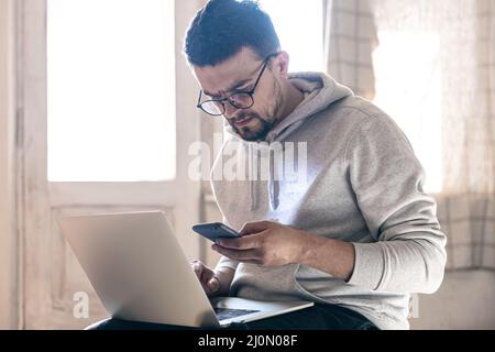 A man with glasses is working on a laptop. Stock Photo