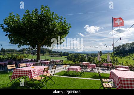 Idyllic outdoor restaurant with a great view and colorful table settings in a grassy backyard terrace in the Swiss Alps Stock Photo
