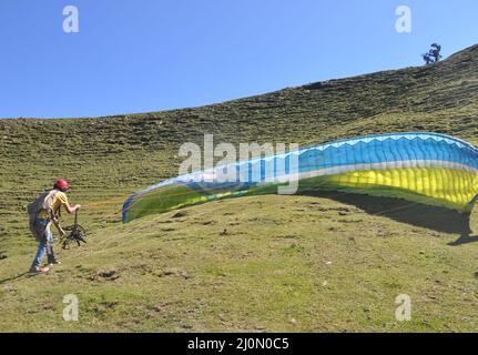 A unidentified male paraglider preparing parachute for flight in the sky Stock Photo