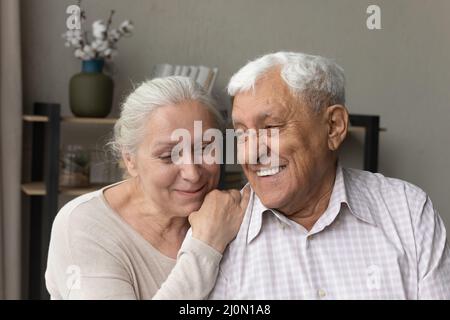 Loving wife and grey-haired husband smiling hugging indoor Stock Photo