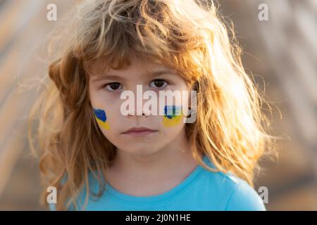 No war, stop war, russian aggression. Ukraine flag on kids cheek. Close up kids face. Stock Photo