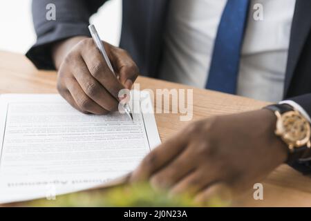 Crop ethnic businessman signing papers Stock Photo