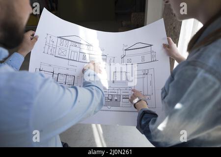 Colleagues holding blueprint and discussing on project at office Stock Photo