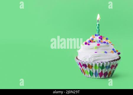 Close up delicious cupcake with burning candle green background Stock Photo