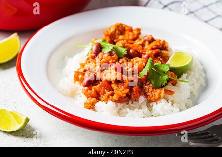 Chili con carne - minced meat with vegetables and beans in tomato sauce with rice in plate. Mexican food concept. Stock Photo