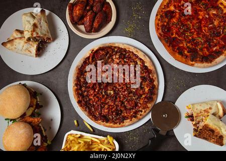 High angle view of table with various pizzas and burgers Stock Photo