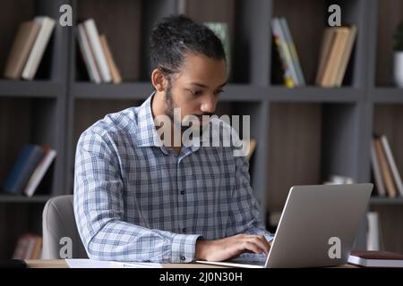 Serious worker guy working on online project at laptop Stock Photo