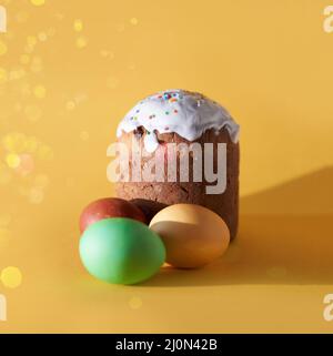 Close-up of colored Easter eggs and a cake on a yellow background with a golden sheen. Orthodox Easter. High quality photo Stock Photo