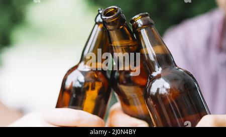 Close up friends clinking brown beer bottles Stock Photo