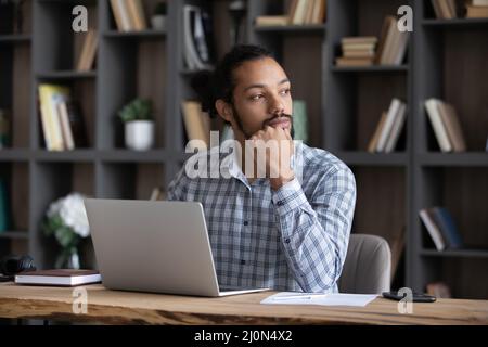 Serious thoughtful young African entrepreneur working at laptop Stock Photo