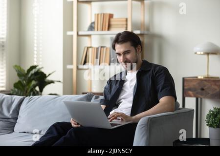 Focused smiling computer user guy working at home Stock Photo