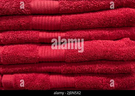 Textured red bath towels stacked close up. Stock Photo