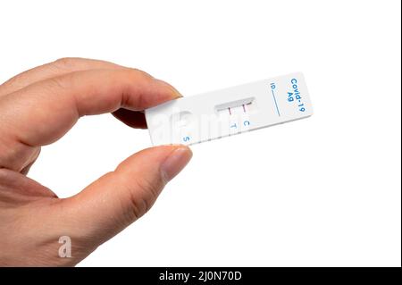 A male hand holding a COVID-19 rapid antigen test kit with two red lines indicating positive. Stock Photo