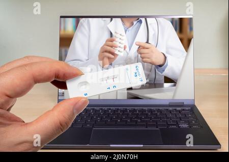 A male hand holding a COVID-19 rapid antigen test kit with two red lines indicating positive. Stock Photo