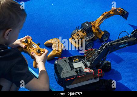 Moscow, Russia. 18th of March, 2022 A boy plays with controlled models of excavators at the National Robotics Championship 'First Robotics Championship - Moscow 3.0' at the Central Exhibition Complex 'Expocentre' in Moscow, Russia Stock Photo