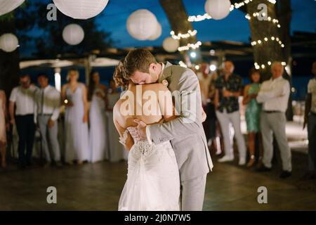 Groom hugs bride in dance in restaurant Stock Photo