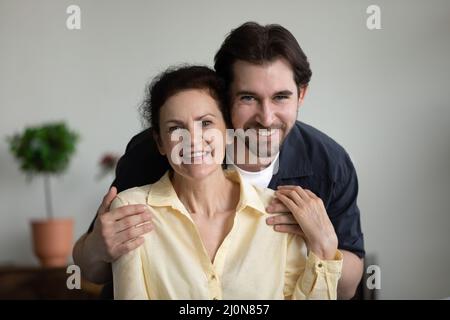 Grateful loving grown son embracing happy senior mom with tenderness Stock Photo