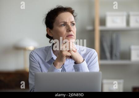 Concerned frustrated mature businesswoman sitting at laptop in office Stock Photo