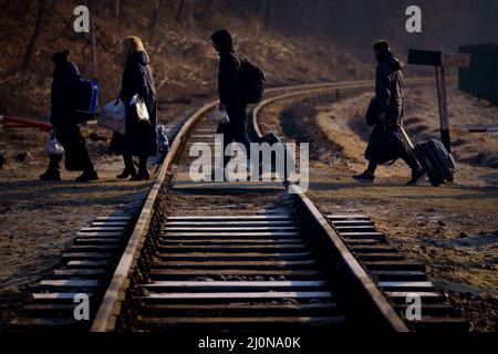 A family from Ukraine walk over a railway line with their luggage after crossing a border point into Poland at Kroscienko, in the south east of the country. Picture date: Saturday March 19, 2022. Stock Photo