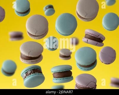 Round baked macarons levitate on a yellow background Stock Photo