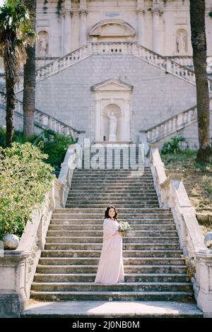 Bride with a bouquet stands on the steps of a luxury villa Stock Photo ...