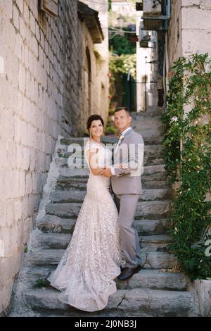 Bride and groom stand on the stone steps near the ancient building Stock Photo