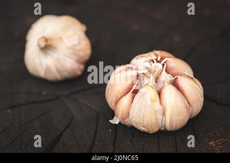 Garlic bulbs and cloves on a black wooden rustic board background, close up Stock Photo