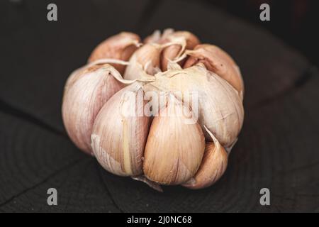 Garlic bulb and cloves on a black wooden rustic board background, close up Stock Photo
