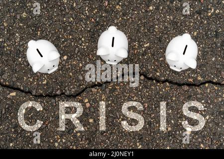 Three Piggy banks standing near the crack in asphalt Stock Photo