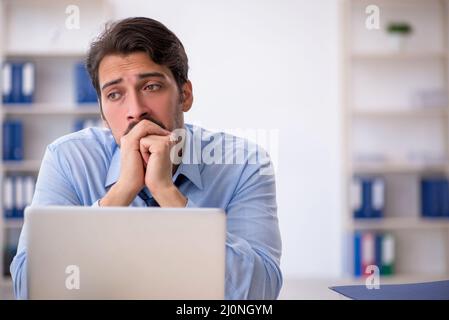 Young male employee suffering at workplace Stock Photo