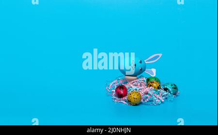 blue Easter egg with ears and colored quail eggs Stock Photo