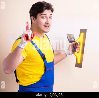 Young contractor employee applying plaster on wall Stock Photo