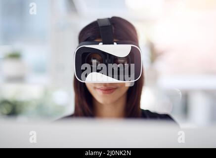 Shes making a profit on every realm of reality. Shot of a young businesswoman wearing a VR headset while working in her office. Stock Photo