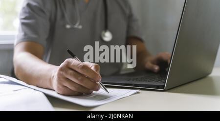 Side view doctor with stethoscope working laptop writing paper . High quality and resolution beautiful photo concept Stock Photo