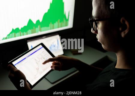 Millenial crypto trader investor analyst looking at computer screen looking at financial data on pc Stock Photo