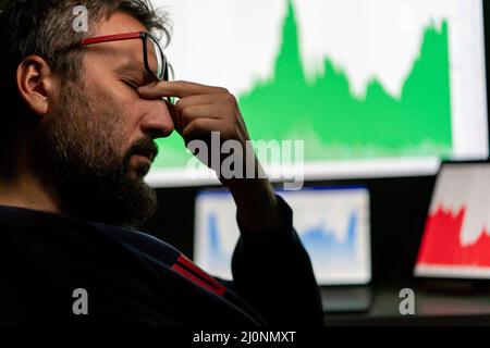 Depressed businessman in front of computer with graph of unsuccessful business on the screen Stock Photo