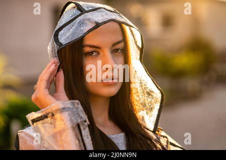Young beautiful woman in hooded raincoat on rainy day Stock Photo