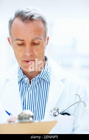 Doctor making rounds. Doctors concentrating while writing on clipboard. Stock Photo