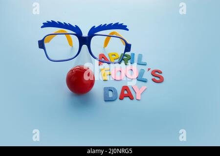 April Fools Day text and funny glasses on blue background Stock Photo