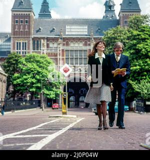 Vintage Amsterdam 1970s, stylish couple of middle aged tourists strolling in front of Rijksmuseum, Holland, Netherlands, Europe, Stock Photo