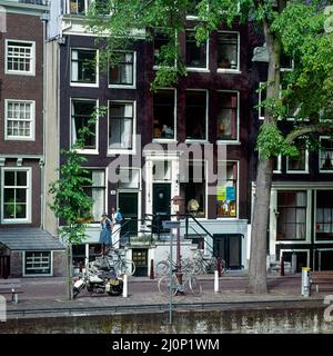 Vintage Amsterdam 1970s, stylish young couple strolling, houses beside canal, Holland, Netherlands, Europe, Stock Photo