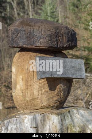 Carved figure of wooden mushroom cep boletus in the forest with empty wooden board in the middle. Stock Photo