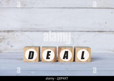 deal concept written on wooden cubes or blocks, on white wooden background. Stock Photo