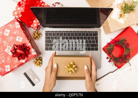 Woman holding gift box while shopping online table with christmas decoration. High quality and resolution beautiful photo concep Stock Photo