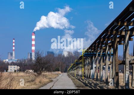 Distant view of a coal-fired power plant. Smoking chimneys and steam from cooling towers. Photo taken on a sunny day, Contrast lighting. Stock Photo