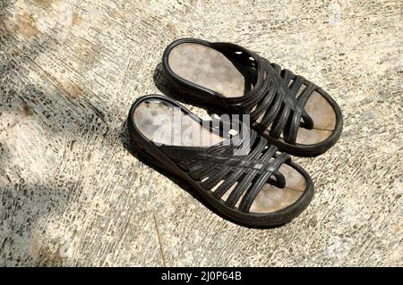Worn out unbranded sandals on the cement floor Stock Photo
