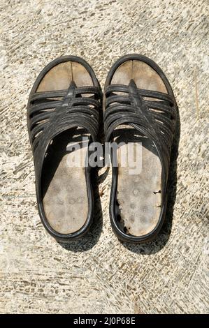 Worn out unbranded sandals on the cement floor Stock Photo