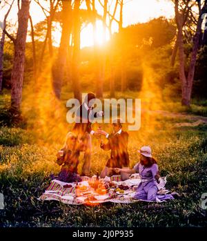 Vintage Italy 1970s, 2 couples of cheerful friends having a picnic at sunset, solar light flare, late afternoon, Roman countryside, Lazio, Europe, Stock Photo