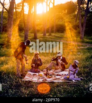 Vintage Italy 1970s, 2 couples of cheerful friends having a picnic at sunset, solar light flare, late afternoon, Roman countryside, Lazio, Europe, Stock Photo